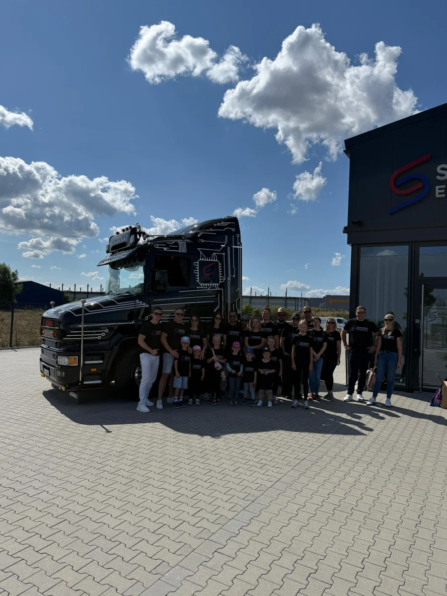 Schaknat Elektronik Team vor schwarzem Scania LKW